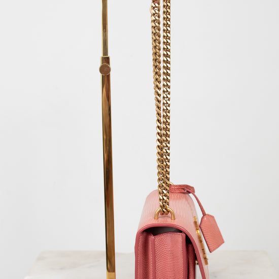 Side view of pink lizard bag with gold chain straps on gold stand