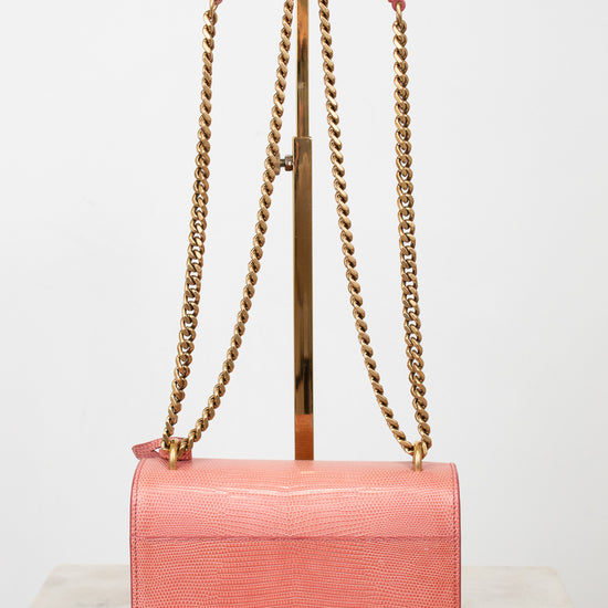 Back view of pink lizard bag with gold chain straps on gold stand 