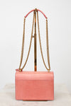 Back view of pink lizard bag with gold chain straps on gold stand 