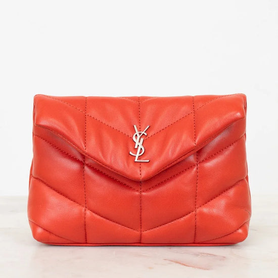 Red quilted handbag with a brand logo on a light beige background