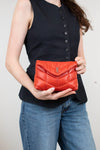 Person holding a red YSL purse against a plain background