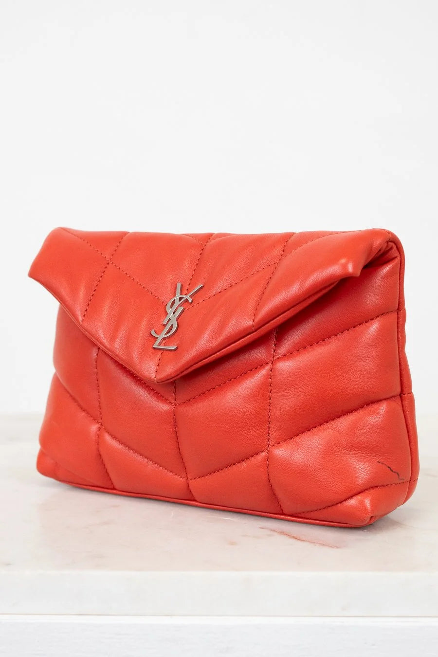 Red quilted handbag with a brand logo on a light background
