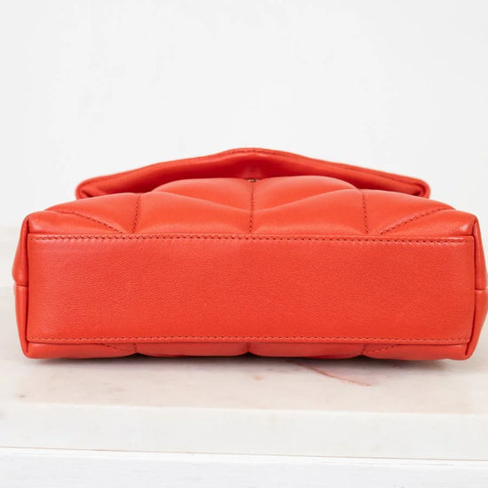 Orange quilted handbag on a white background