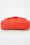 Orange quilted handbag on a white background
