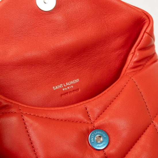 Close-up of a red quilted handbag with 'Saint Laurent' branding.