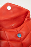 Close-up of a red quilted handbag with 'Saint Laurent' branding.