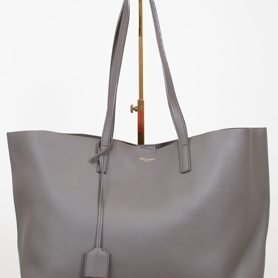 Gray tote bag with a "Saint Laurent" brand tag on a white background