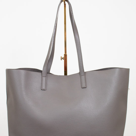 Gray tote bag on a gold purse stand with a white background