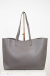 Gray tote bag on a gold purse stand with a white background
