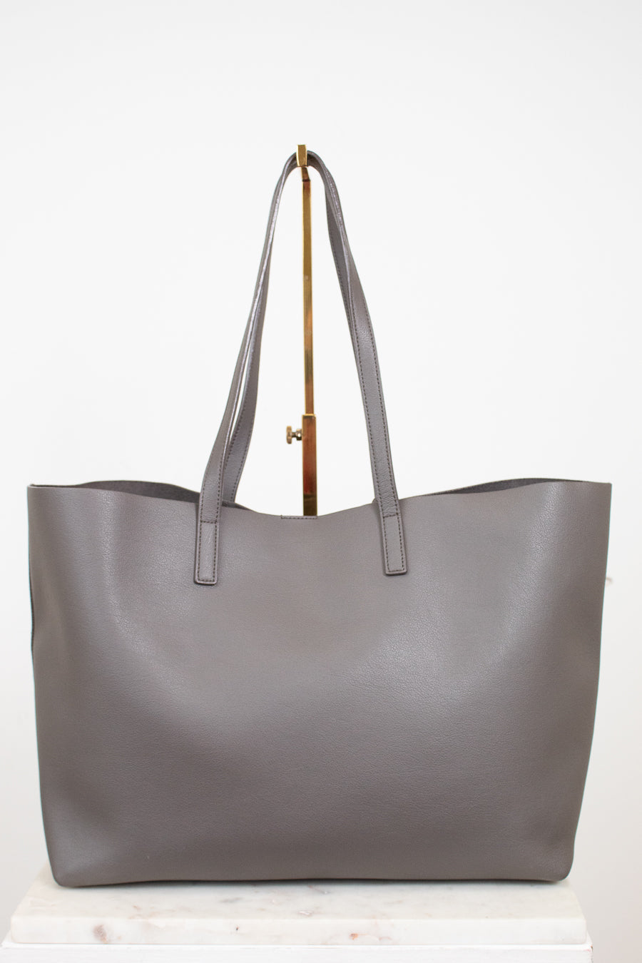 Gray tote bag on a gold purse stand with a white background