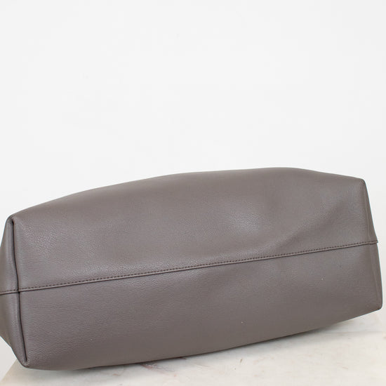 Gray leather bag on a white marble surface with a white background