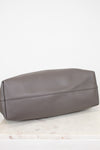 Gray leather bag on a white marble surface with a white background