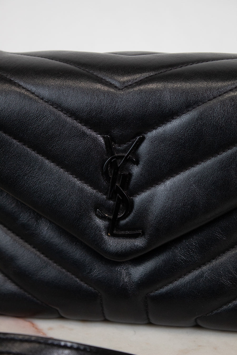 Black quilted handbag with a brand logo on a light background