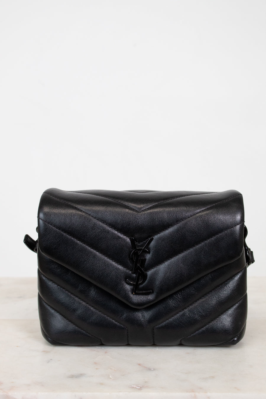 Black quilted handbag on a light gray background