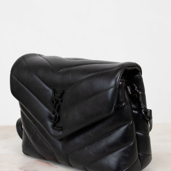 Black leather bag on a marble surface with a white background