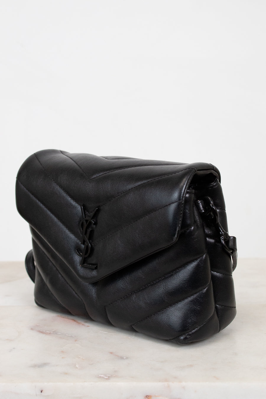 Black leather bag on a marble surface with a white background
