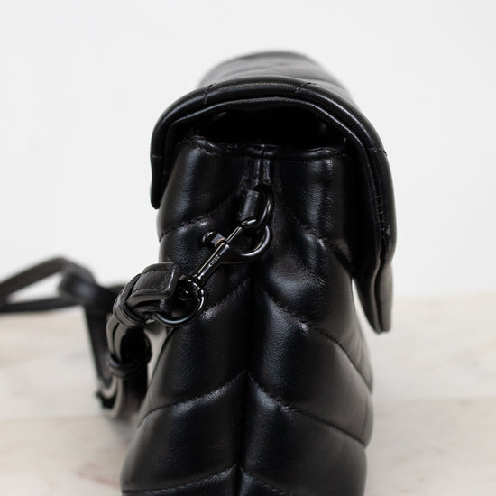 Black quilted handbag with a strap on a light background