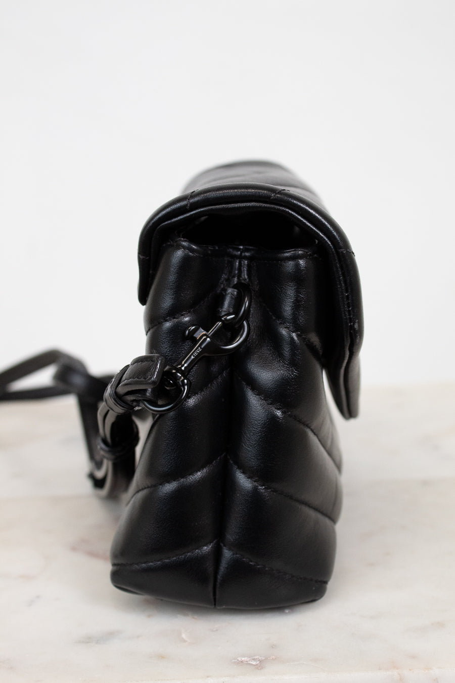 Black quilted handbag with a strap on a light background