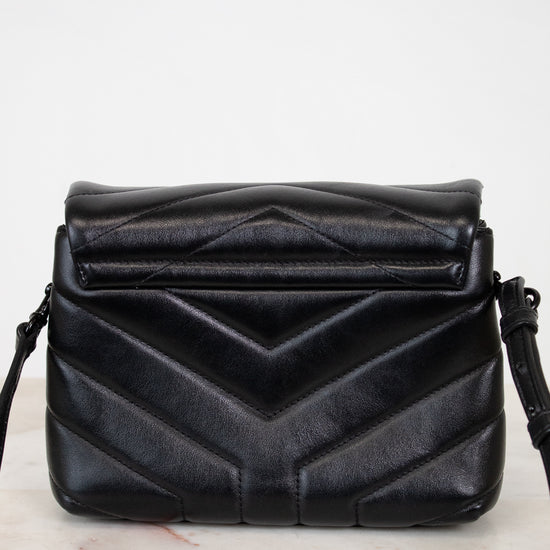Black quilted handbag on a light marble surface