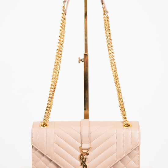 Beige quilted handbag with gold chain strap and logo on a white background