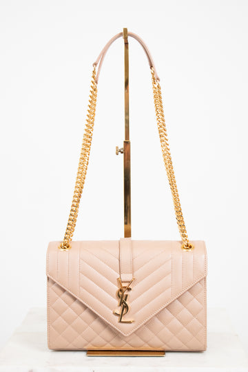 Beige quilted handbag with gold chain strap and logo on a white background