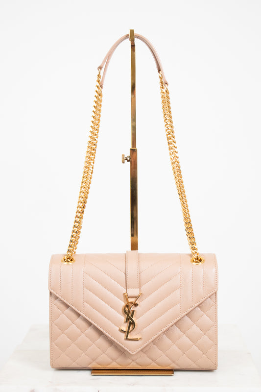 Beige quilted handbag with gold chain strap and logo on a white background