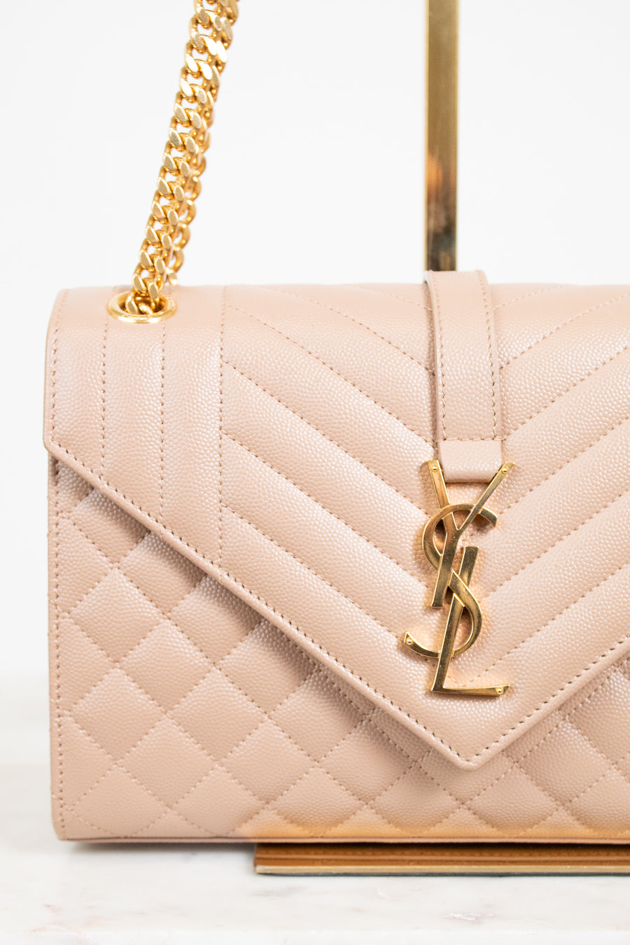 Quilted handbag with gold chain and logo on a light background