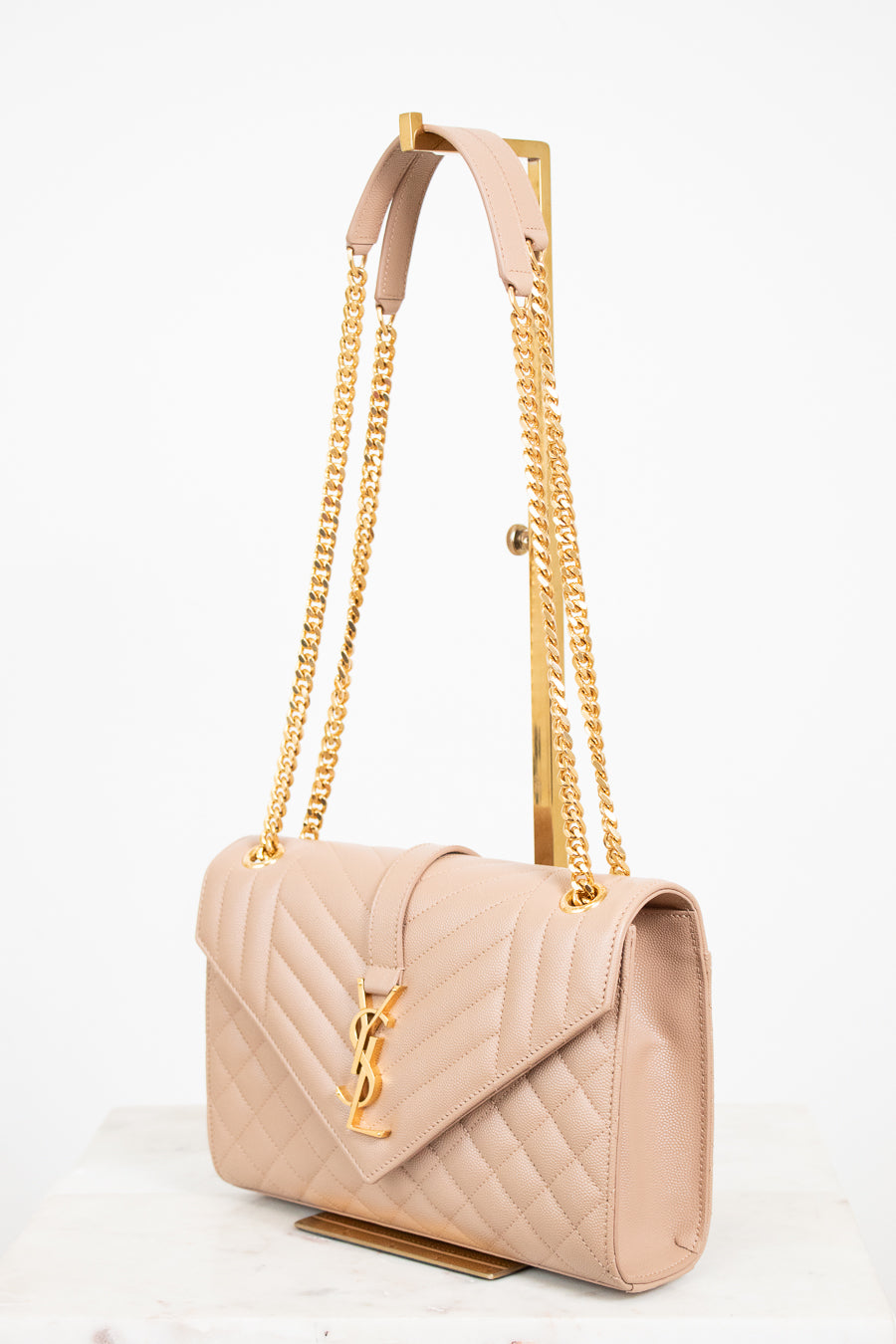 Beige handbag with gold chain strap on a white background