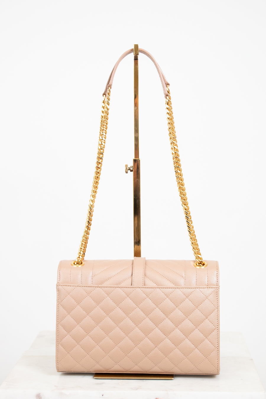 Beige quilted handbag with gold chain strap on a white background