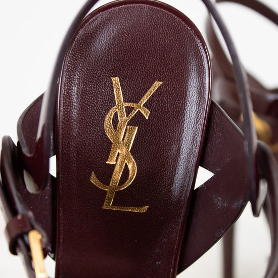 Close-up of a YSL sandal with gold logo on a white background