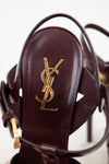 Close-up of a YSL sandal with gold logo on a white background