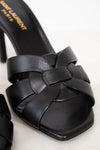 Black sandal with woven straps on a white background