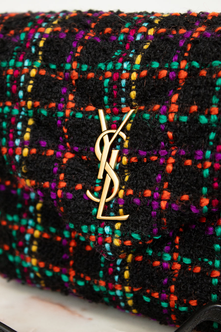 Multicolored textured handbag with YSL logo on a white background