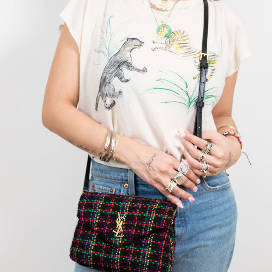 Person holding a colorful tweed handbag with a plain background