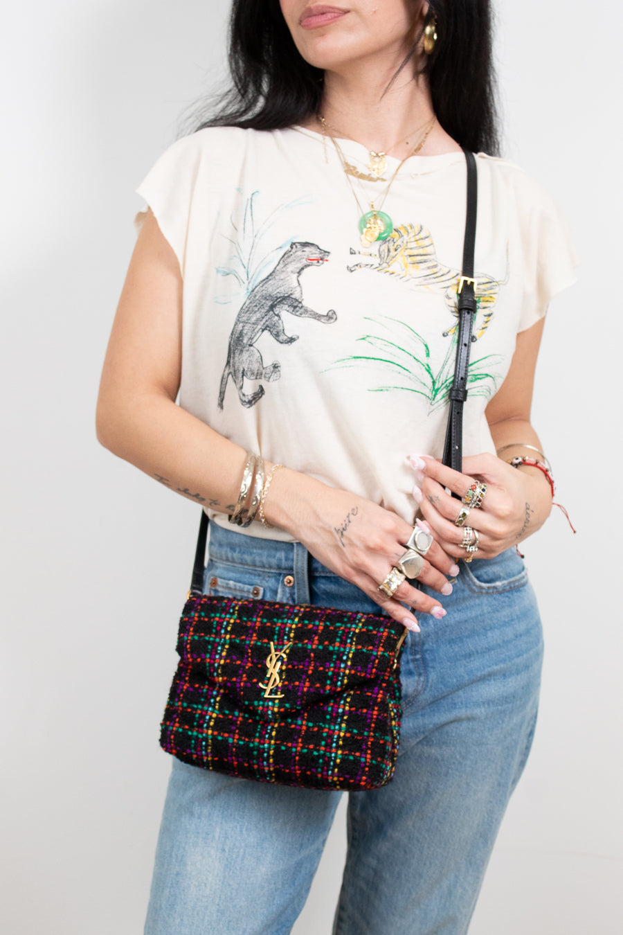 Person holding a colorful tweed handbag with a plain background