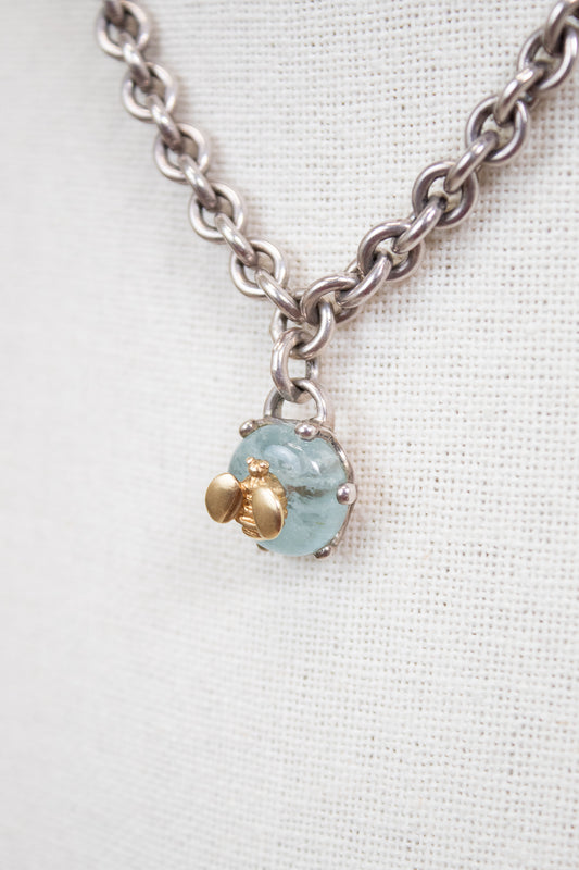 Necklace with a blue stone pendant and gold bee charm on a white background