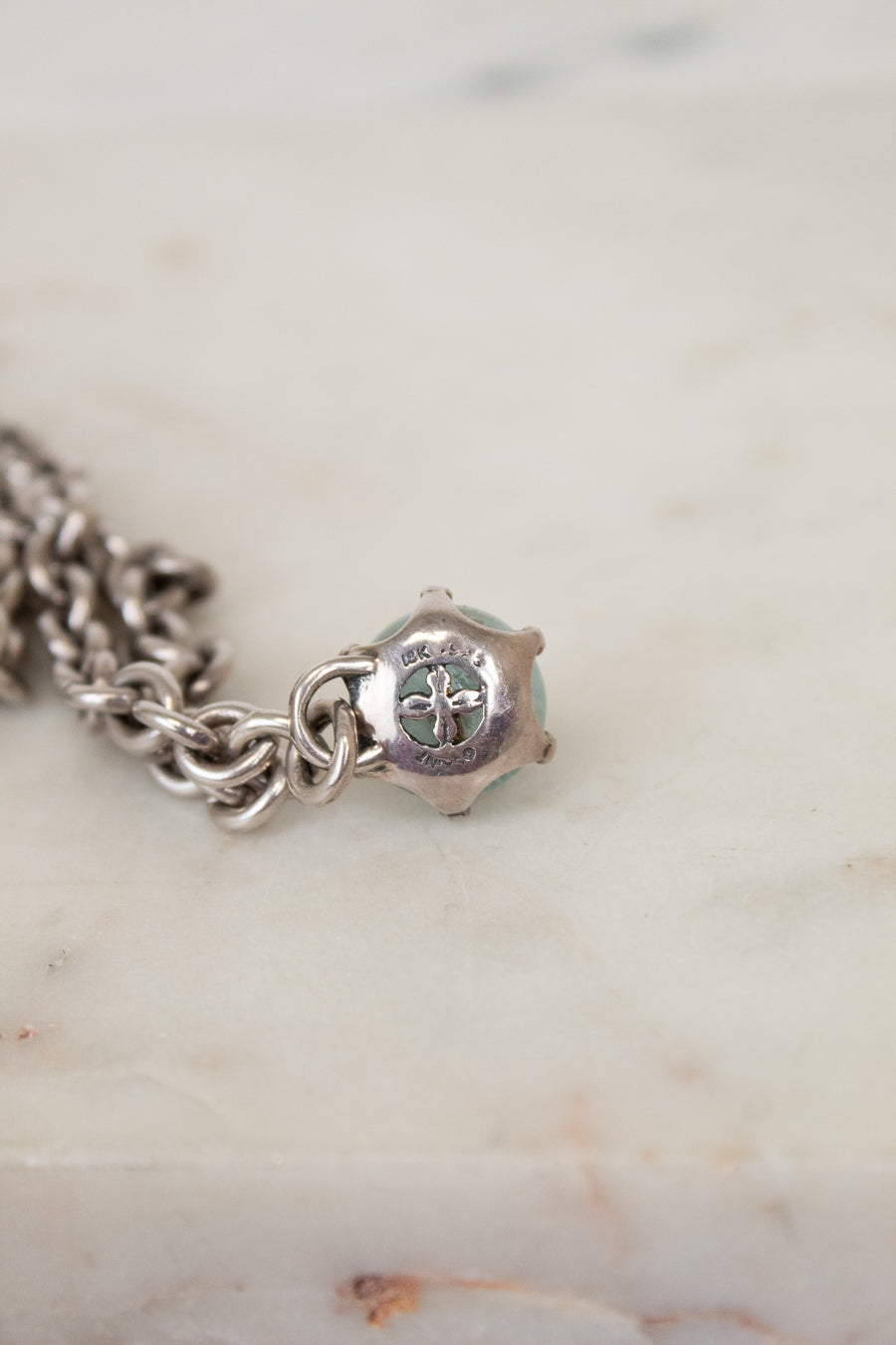 Silver charm bracelet on a marble surface