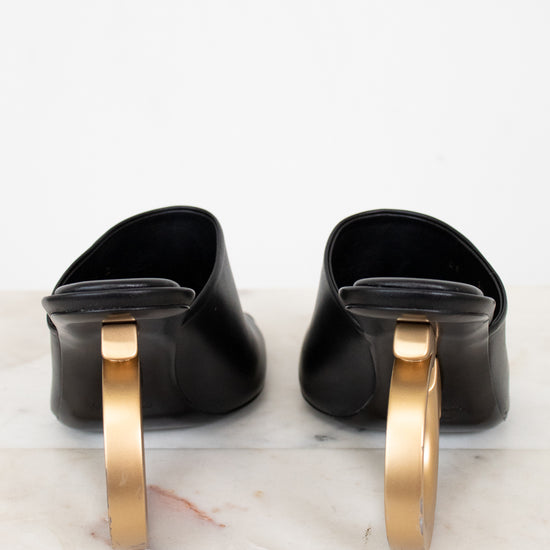 Pair of black shoes with gold heel on a marble surface