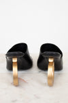 Pair of black shoes with gold heel on a marble surface