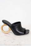 Black open-toe sandal with a gold ring heel on a white background