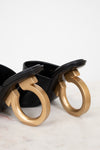 Black heeled shoe with golden heel detail on a light background