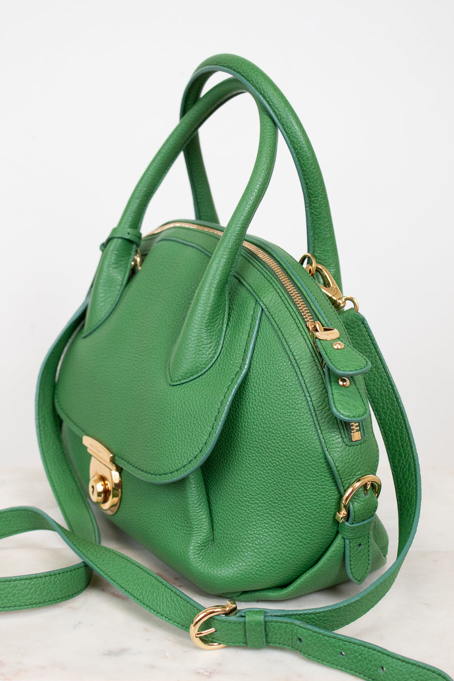 Green handbag with gold accents on a white background