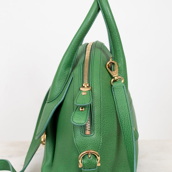 Green handbag with gold zippers on a white background