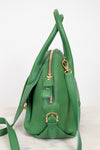 Green handbag with gold zippers on a white background