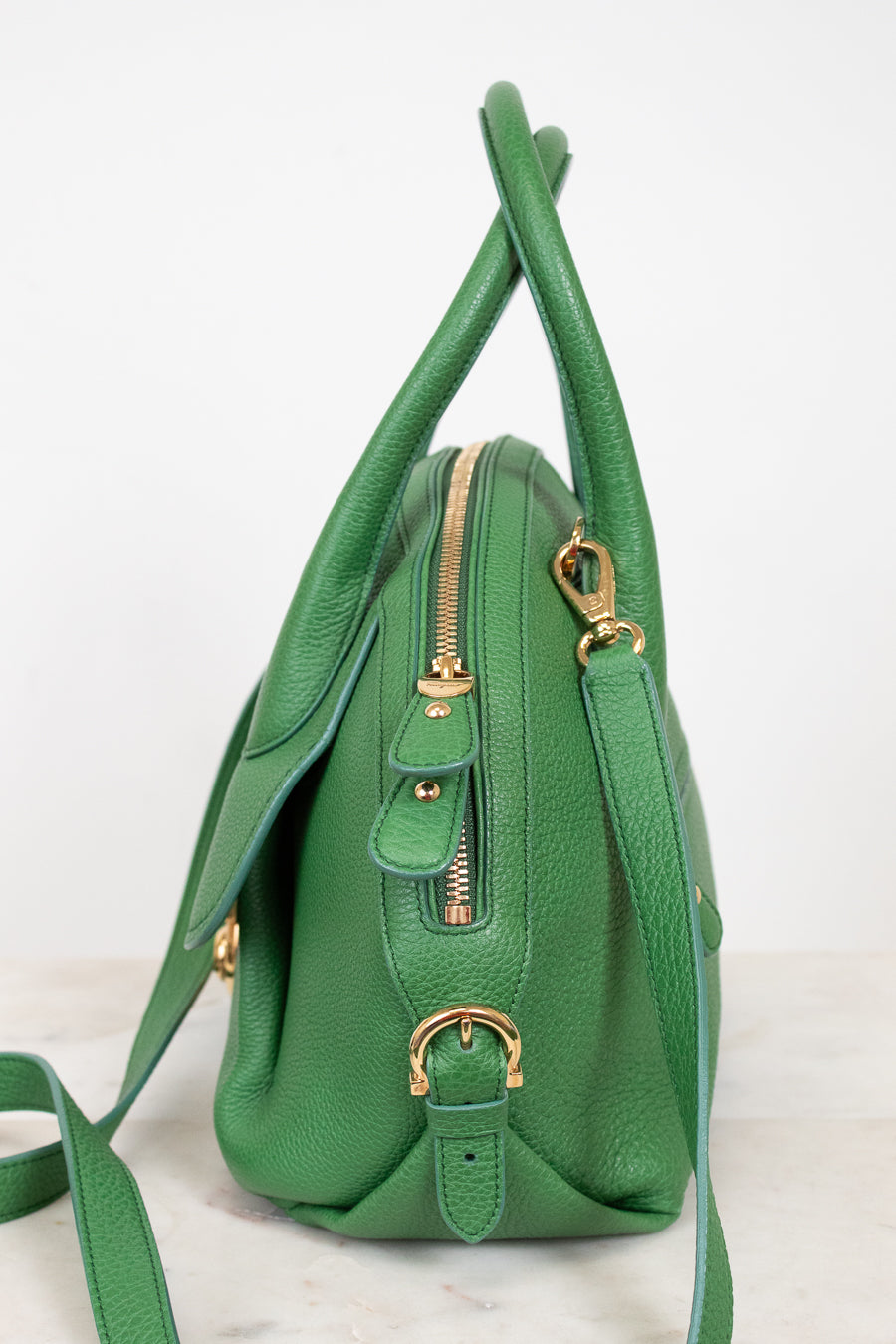 Green handbag with gold zippers on a white background