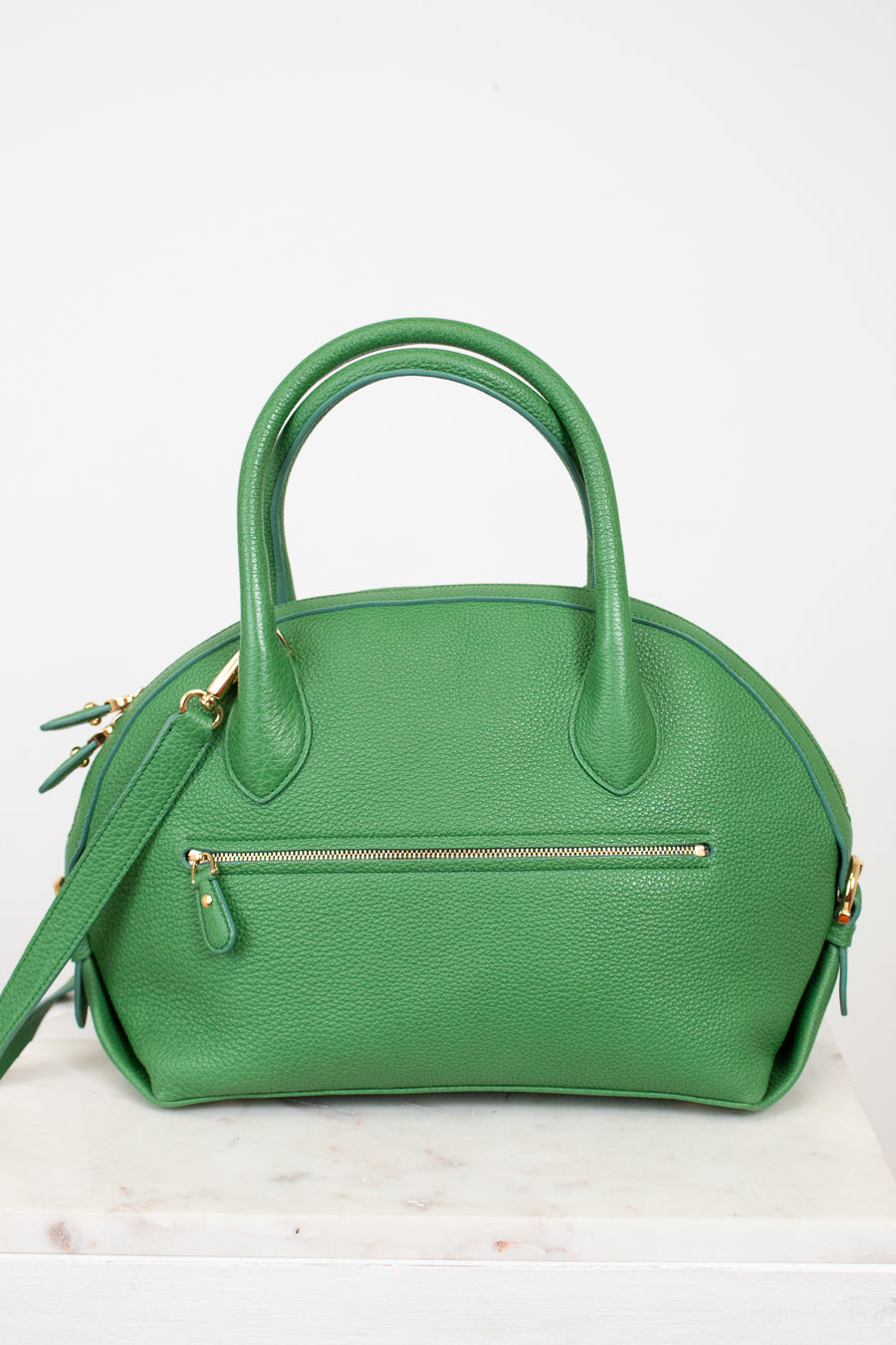 Green handbag with gold accents on a white background