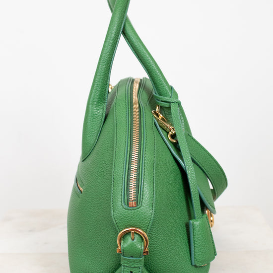Green handbag with gold zipper and hardware on a white background