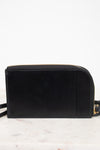 A black leather crossbody bag with gold-tone hardware, resting on a white marble surface against a white background.