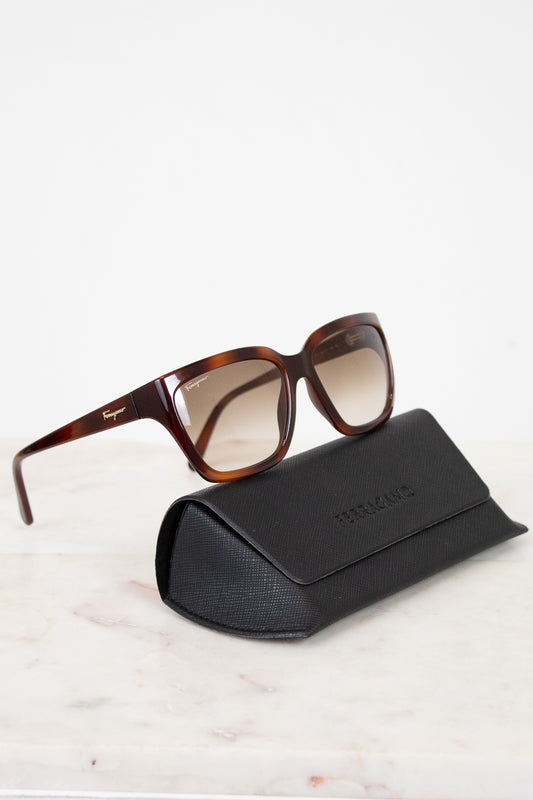 Sunglasses with a black case on a light marble surface