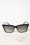 Black cat-eye sunglasses with gradient gray lenses, displayed on a light marble surface against a white background.